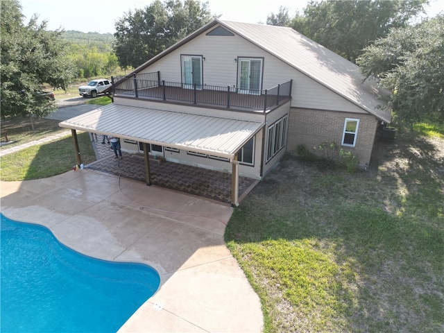 back of property with a lawn, a patio area, and a balcony