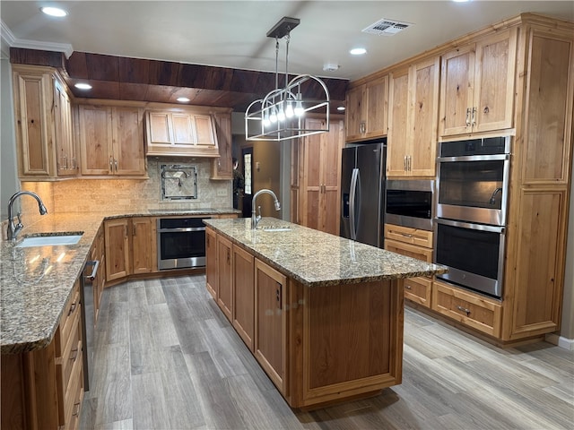 kitchen with light hardwood / wood-style floors, sink, an island with sink, and stainless steel appliances