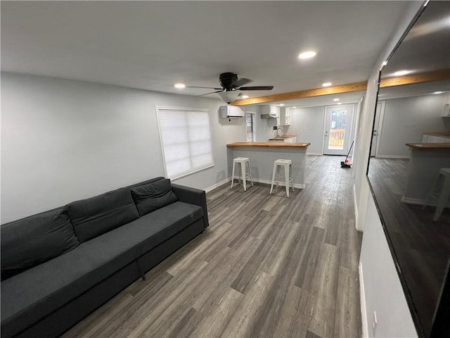 living room featuring baseboards, a wall mounted AC, wood finished floors, and recessed lighting