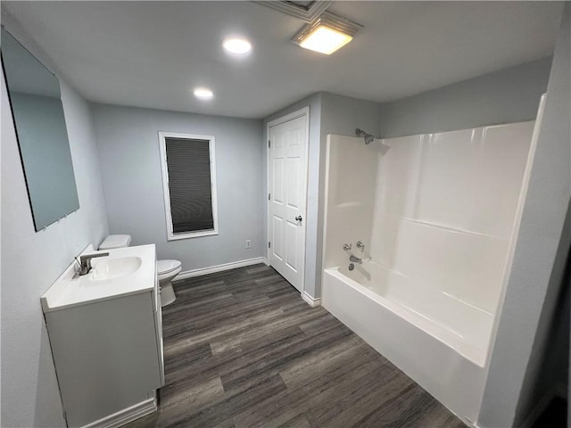 full bath with toilet, washtub / shower combination, vanity, wood finished floors, and baseboards
