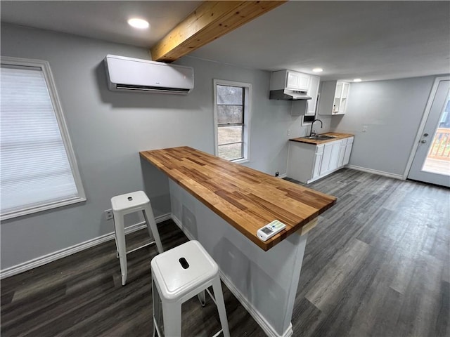 interior space with a breakfast bar, a wall mounted air conditioner, a peninsula, and white cabinetry