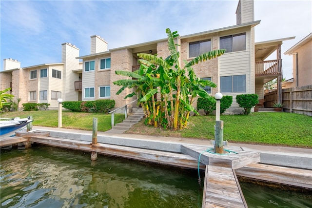 view of dock with a lawn and a water view