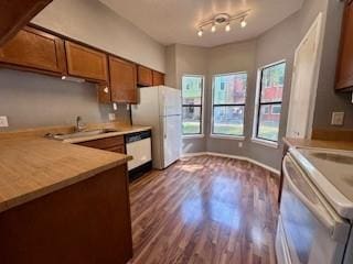 kitchen with dark wood-style flooring, brown cabinets, freestanding refrigerator, electric stove, and dishwashing machine