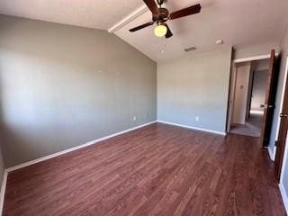 spare room with baseboards, ceiling fan, dark wood-style floors, and vaulted ceiling with beams