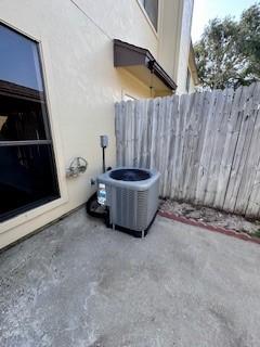 details featuring fence, stucco siding, and central AC