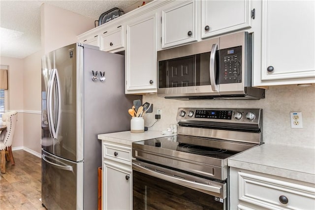 6309 Brianna Cir, Corpus Christi, TX 78414 - kitchen with appliances with stainless steel finishes, light countertops, white cabinets, light wood finished floors, and a textured ceiling