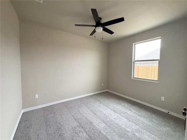 carpeted spare room featuring ceiling fan and baseboards