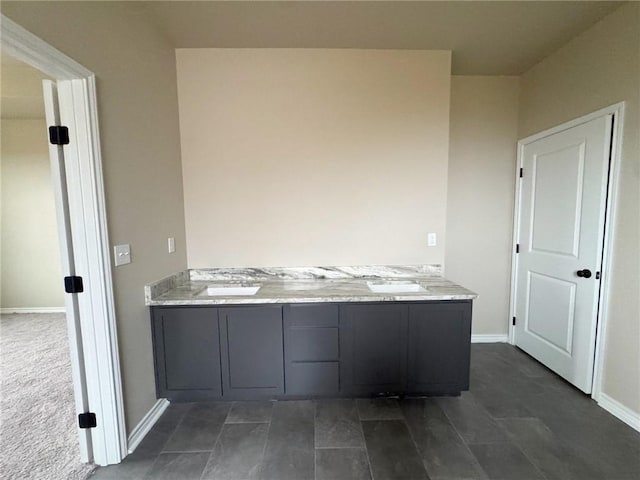 full bathroom with double vanity, a sink, and baseboards