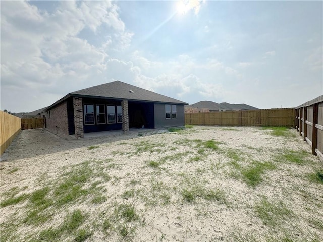 rear view of property with brick siding and a fenced backyard