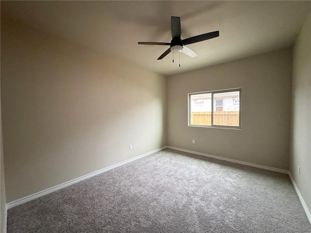 spare room with carpet floors, a ceiling fan, and baseboards