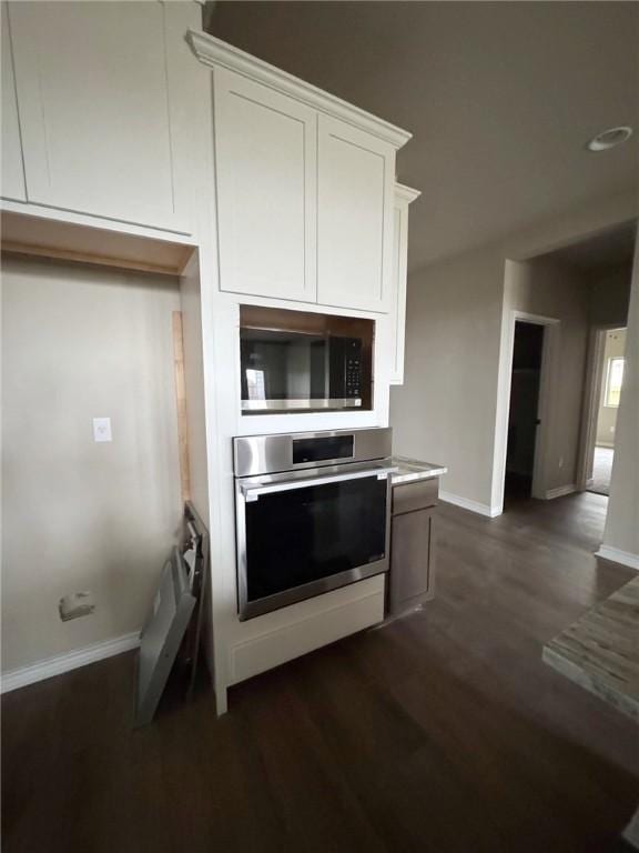 kitchen featuring baseboards, white cabinetry, stainless steel appliances, and dark wood-style flooring