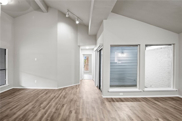 interior space featuring lofted ceiling with beams, light hardwood / wood-style floors, and track lighting