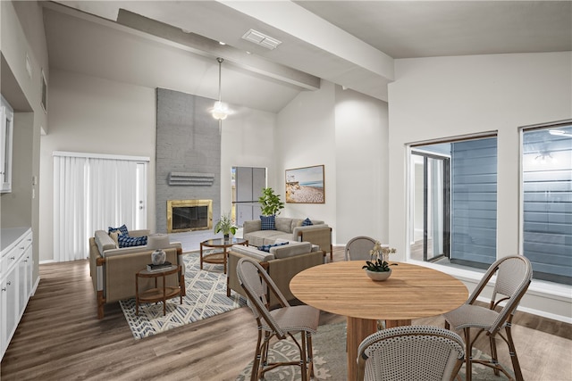 dining space with a fireplace, hardwood / wood-style floors, high vaulted ceiling, and beamed ceiling