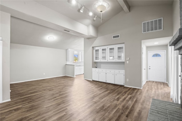 unfurnished living room featuring beam ceiling, high vaulted ceiling, and dark wood-type flooring