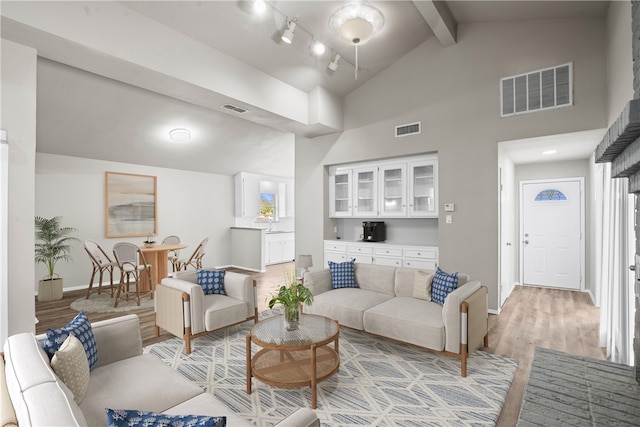 living room with beamed ceiling, light hardwood / wood-style floors, high vaulted ceiling, and a healthy amount of sunlight