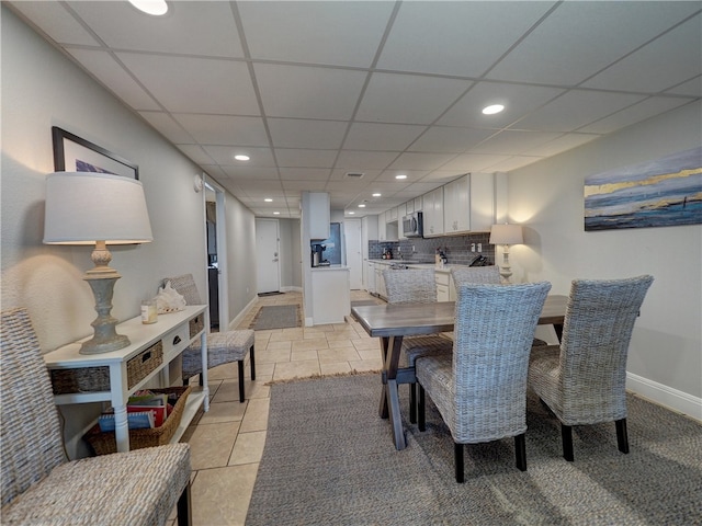 dining space with light tile patterned floors and a drop ceiling