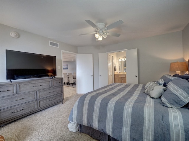 bedroom featuring connected bathroom, light colored carpet, and ceiling fan