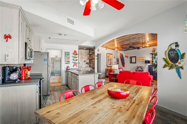 dining area with a textured ceiling, dark wood-type flooring, sink, and ceiling fan