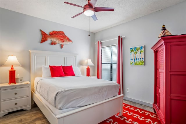 bedroom featuring ceiling fan, dark hardwood / wood-style floors, and a textured ceiling