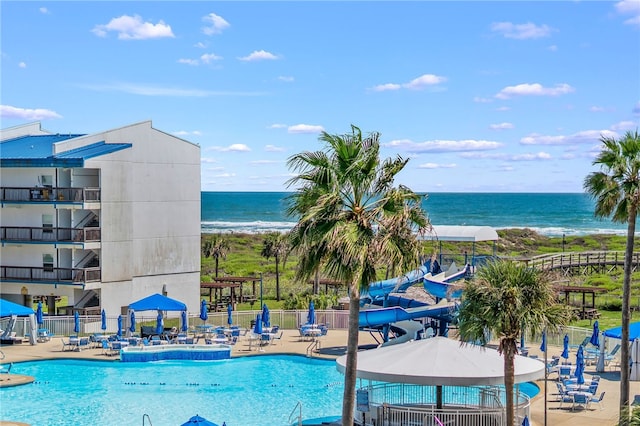 view of pool with a water slide, a patio, and a water view