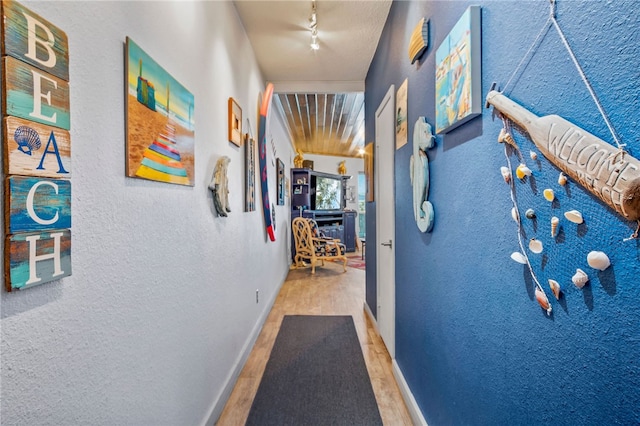 corridor featuring hardwood / wood-style flooring and rail lighting