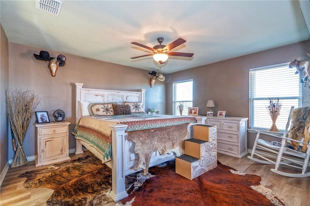 bedroom featuring hardwood / wood-style flooring, ceiling fan, and multiple windows