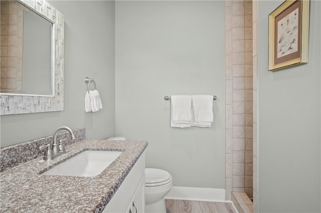 bathroom with tiled shower, vanity, and toilet