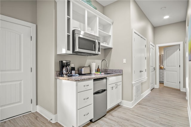 kitchen featuring light wood-type flooring, white cabinetry, and sink