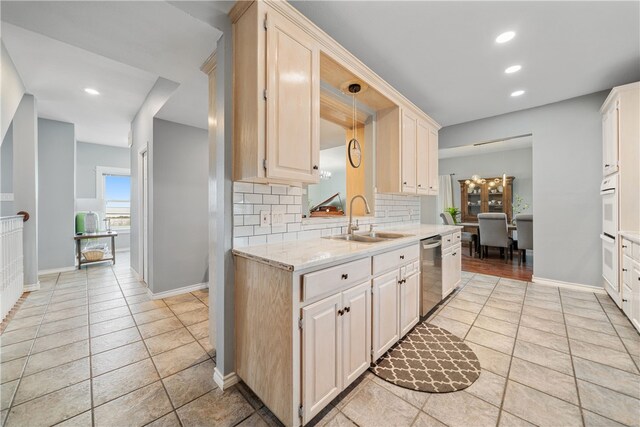 kitchen featuring sink, hanging light fixtures, tasteful backsplash, light stone countertops, and stainless steel dishwasher