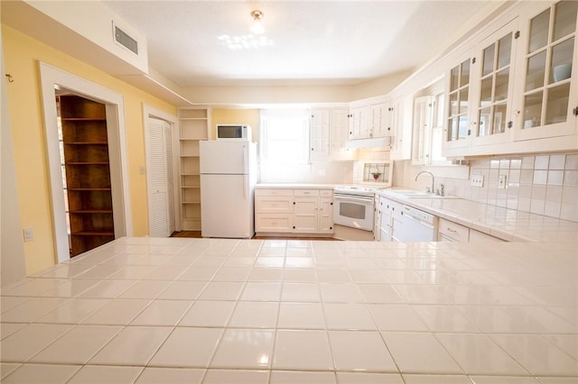 1107 N Adams St, Beeville, TX 78102 - kitchen featuring white appliances, a sink, tile counters, and plenty of natural light