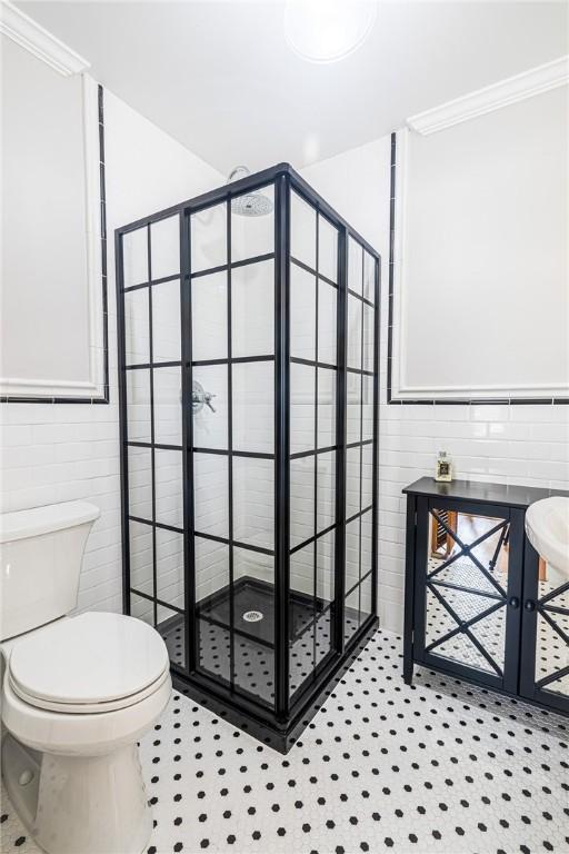 1107 N Adams St, Beeville, TX 78102 - bathroom with tile walls, a stall shower, ornamental molding, and toilet