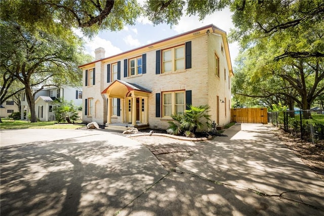 1107 N Adams St, Beeville, TX 78102 - colonial-style house featuring concrete driveway, a chimney, and brick siding