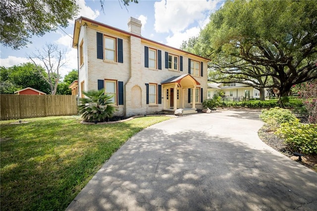 1107 N Adams St, Beeville, TX 78102 - colonial house featuring a chimney, concrete driveway, and brick siding