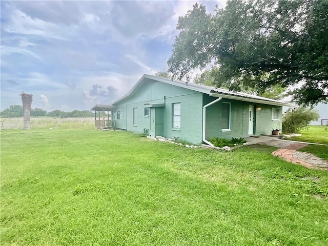 105 Canal St, Mathis, TX 78368 - view of side of home with concrete block siding, a yard, and a metal roof
