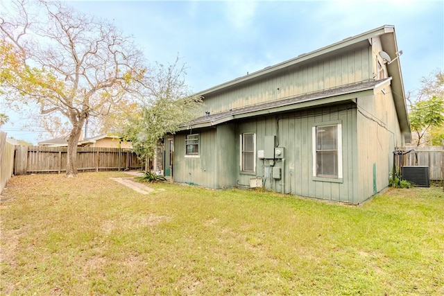 rear view of house featuring cooling unit and a lawn