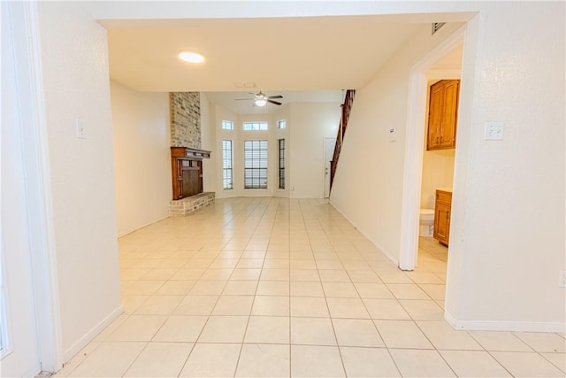 empty room featuring light tile patterned flooring, ceiling fan, and a fireplace