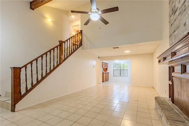 unfurnished living room featuring a high ceiling, light tile patterned flooring, ceiling fan, and beam ceiling