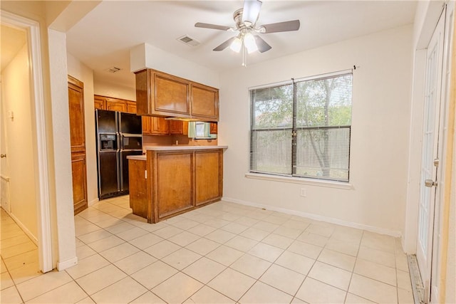 kitchen with black fridge, ceiling fan, kitchen peninsula, and light tile patterned floors