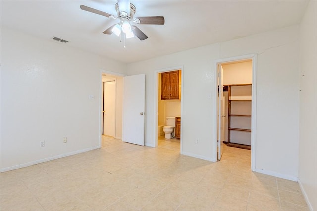 unfurnished bedroom with ceiling fan, ensuite bathroom, a spacious closet, and a closet