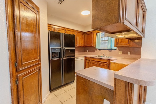 kitchen featuring sink, black fridge, dishwasher, light tile patterned flooring, and kitchen peninsula