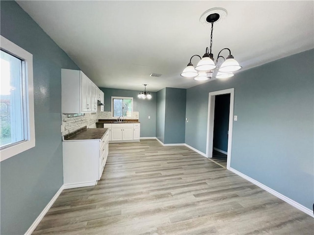 4313 Molina Dr, Corpus Christi, TX 78416 - kitchen with a chandelier, a sink, white cabinetry, and baseboards