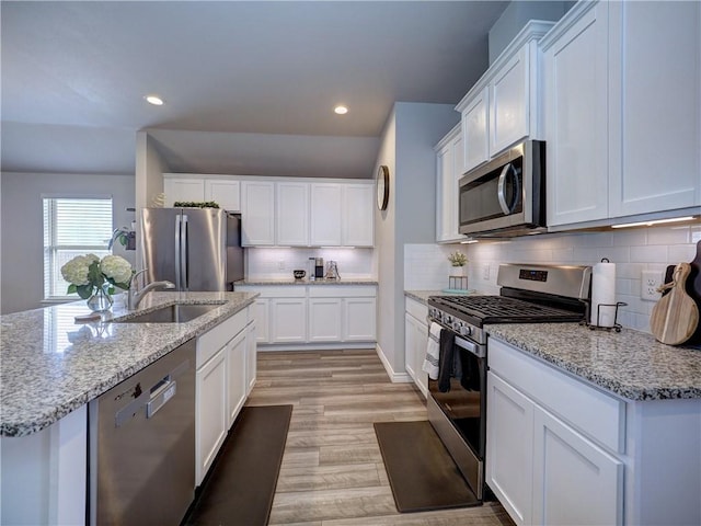 2693 Excelsior Blvd, Corpus Christi, TX 78415 - kitchen featuring stainless steel appliances, white cabinetry, decorative backsplash, light wood-type flooring, and recessed lighting