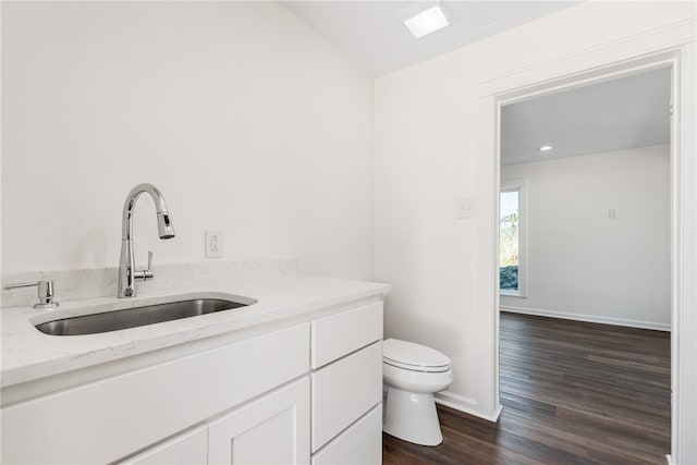 bathroom with toilet, vanity, and wood-type flooring