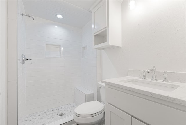 bathroom with a tile shower, vanity, and toilet