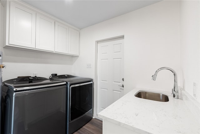 clothes washing area featuring washer and clothes dryer, dark wood-type flooring, cabinets, and sink