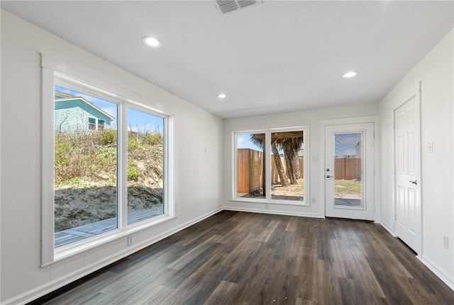 spare room with dark hardwood / wood-style flooring and plenty of natural light