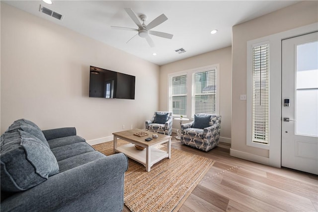 living area with ceiling fan, baseboards, light wood-style floors, and visible vents