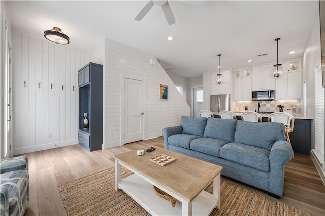 living room with ceiling fan, light wood finished floors, and recessed lighting