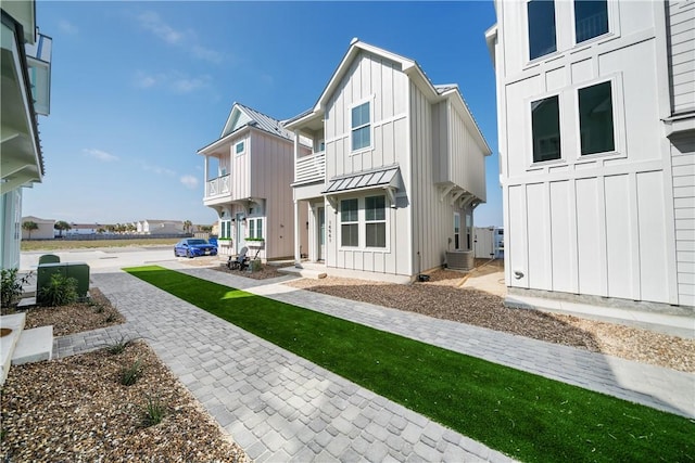 rear view of property with board and batten siding, a standing seam roof, a balcony, and metal roof