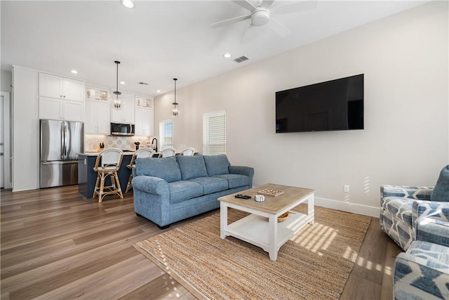 living room featuring light wood-style flooring, visible vents, recessed lighting, and ceiling fan
